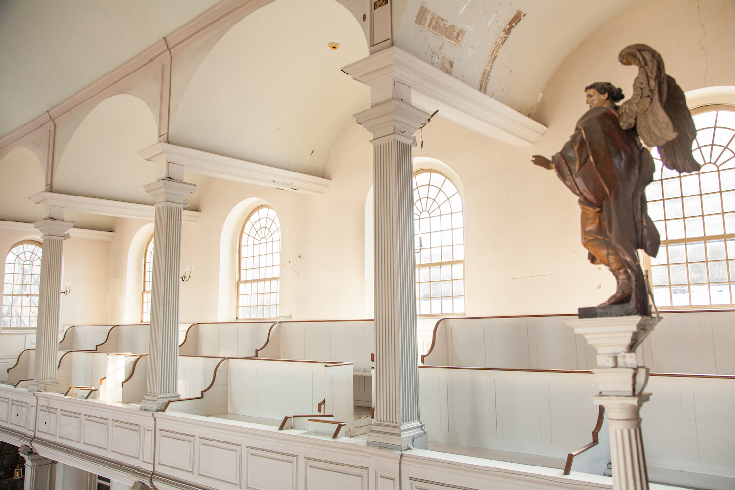 A carved angel overlooking the pews in the gallery of Old North Church.