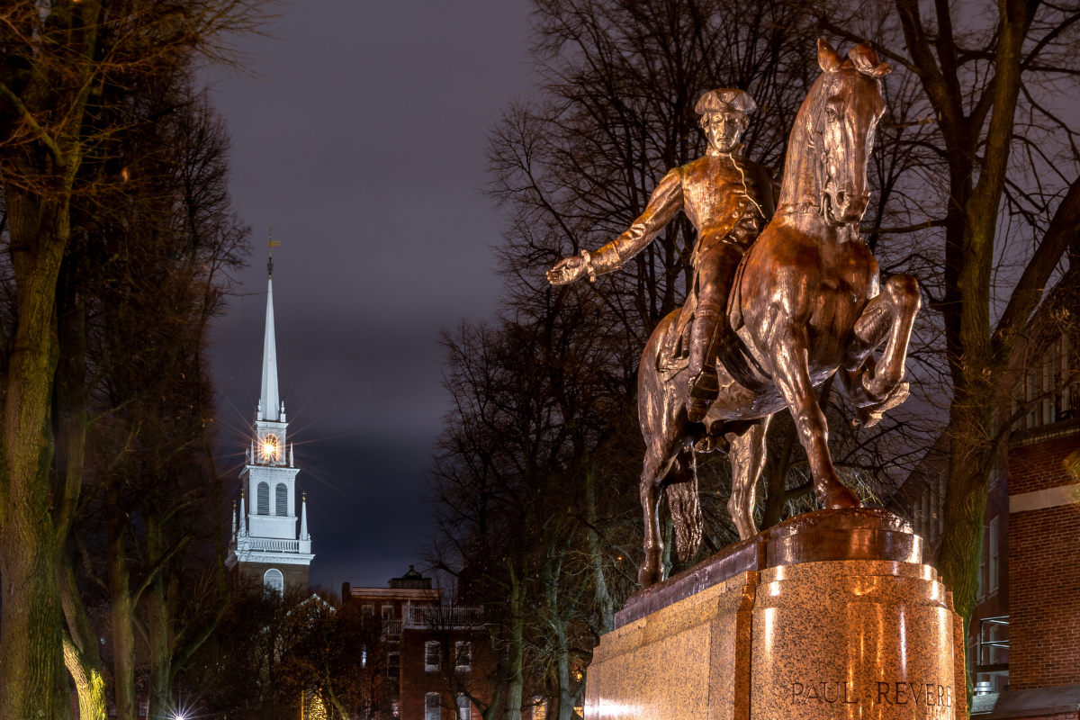 Boston's statue of Paul Revere with lanterns shining from Old North Church's steeple.