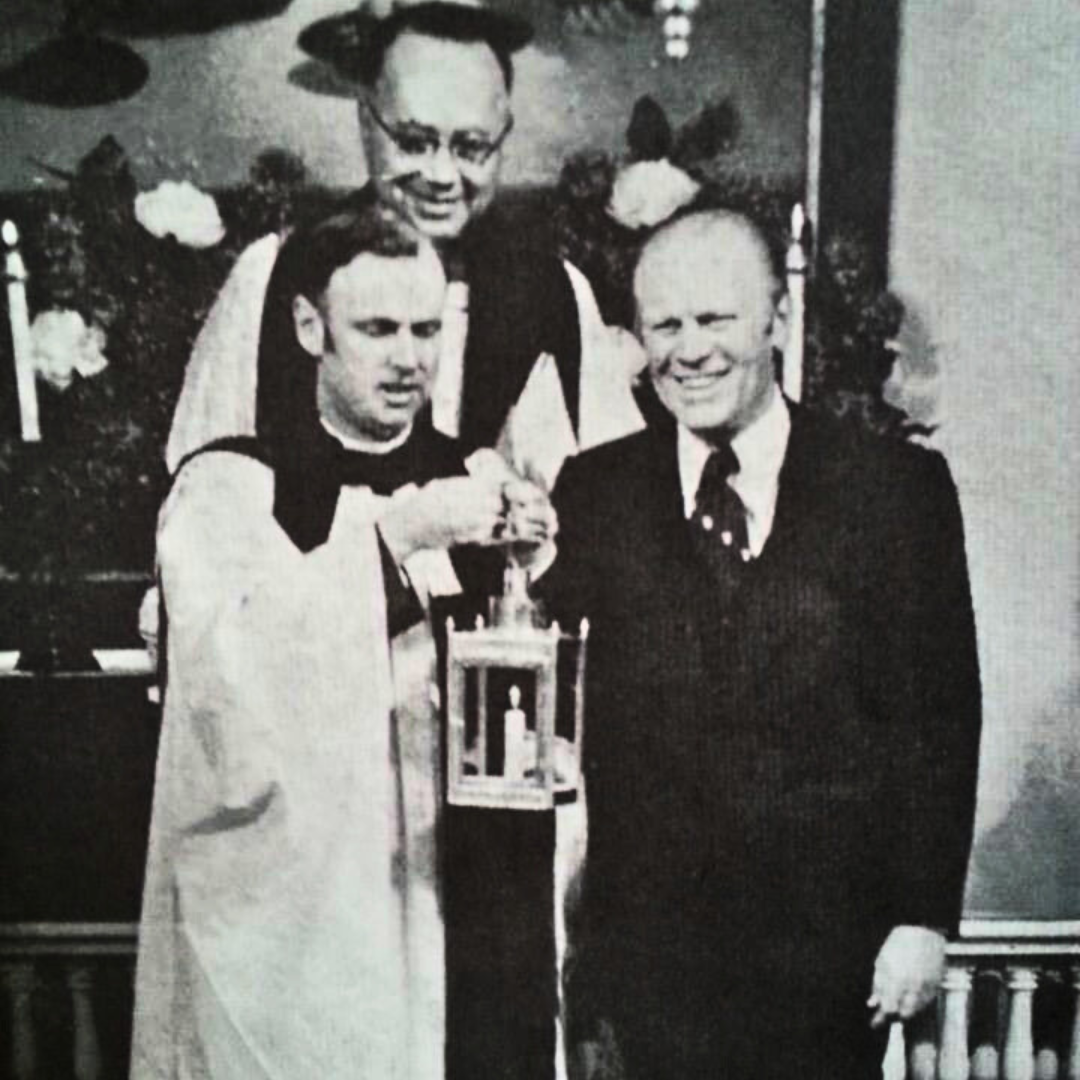 President Ford and Rev. Golledge hold a lantern at the Old North Church in 1975. Another clergy member stands behind them. 